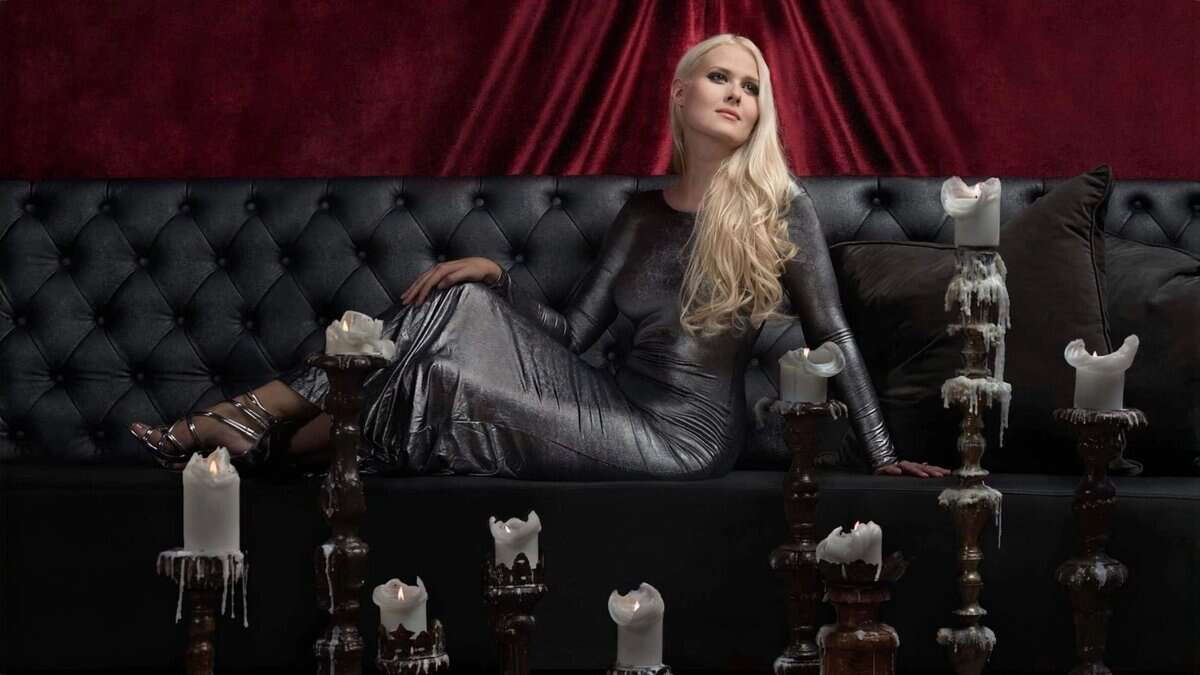 Zoe Marie Federoff in black leather dress with candles, dark velvet background, elegant and mysterious atmosphere.